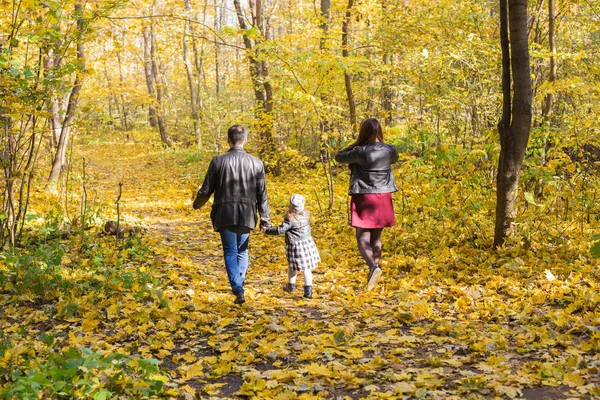 Personer, familj och fritid koncept - lycklig familj med dotter promenader i höst park, bakifrån — Stockfoto