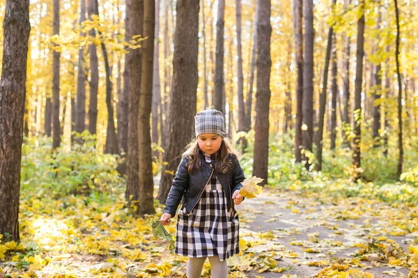 Έννοια πτώση, της φύσης και της παιδικής ηλικίας - ευτυχισμένο παιδάκι παίζει στο πάρκο με τα κίτρινα φύλλα — Φωτογραφία Αρχείου