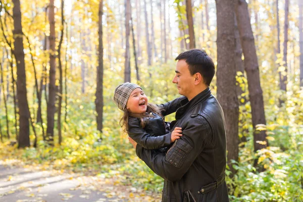 Paternité, concept de famille et de loisirs - père tenant sa petite fille dans ses bras dans un parc d'automne — Photo