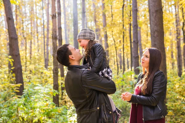 Concepto de personas, familia y ocio - padre feliz sosteniendo a su hijita en el parque de otoño — Foto de Stock