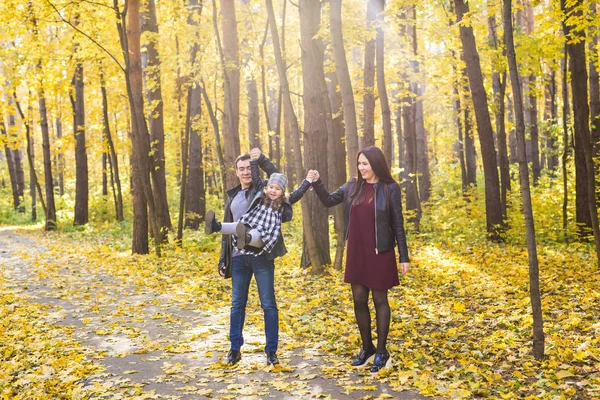 Familie, vallen, mensen concept - gemengd ras jonge gezin wandelen in het park op in herfstdag — Stockfoto