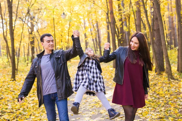 Family, fall, people concept - mixed race young family walking in park on in autumn day — Stock Photo, Image