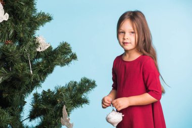 Noel ağacı üzerinde mavi arka plan ile küçük kız