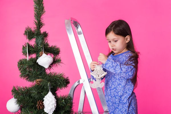 Liten flicka med julgran på rosa bakgrund — Stockfoto