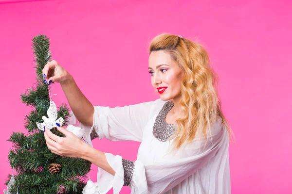 Άνθρωποι, τις διακοπές και τα Χριστούγεννα έννοια - γυναίκα διακόσμηση του Χριστουγεννιάτικου δέντρου σε ροζ φόντο — Φωτογραφία Αρχείου