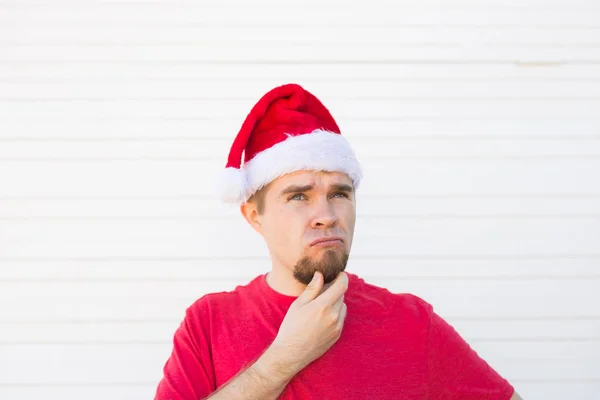 Navidad, la gente, el concepto de emociones - Papá Noel insatisfecho en el sombrero de Navidad mira hacia arriba — Foto de Stock