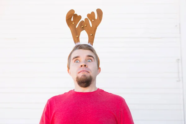 Concepto de vacaciones, Navidad y personas - Hombre sorprendido en traje de ciervo de Navidad sobre fondo blanco — Foto de Stock