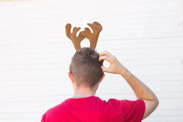 Jul, helgdagar och människor koncept - en mans huvud med rådjur horn på den. Man skrapar sin huvud, rygg syn — Stockfoto