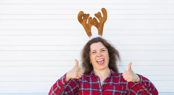 Felice bella donna in costume di Natale con corna di cervo sulla testa gesticolando pollici su sfondo bianco con spazio copia — Foto Stock