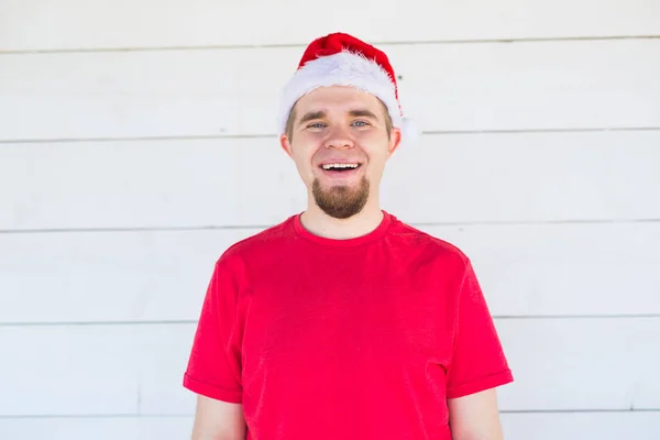 Boże Narodzenie, wakacje, ludzie koncepcja - młody człowiek zabawny w santa hat i koszuli uśmiecha się na białe tło — Zdjęcie stockowe