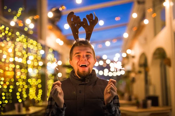 Concepto de Navidad y vacaciones - Hombre feliz en traje de ciervo de Navidad con bengala — Foto de Stock
