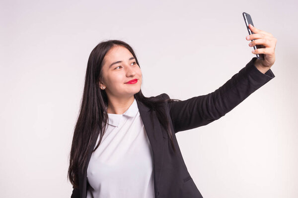 Young asian woman making selfie in studio on white background