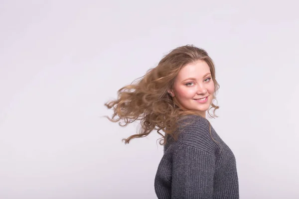 Mulher loira sorridente com cabelo voador no fundo branco com espaço de cópia — Fotografia de Stock