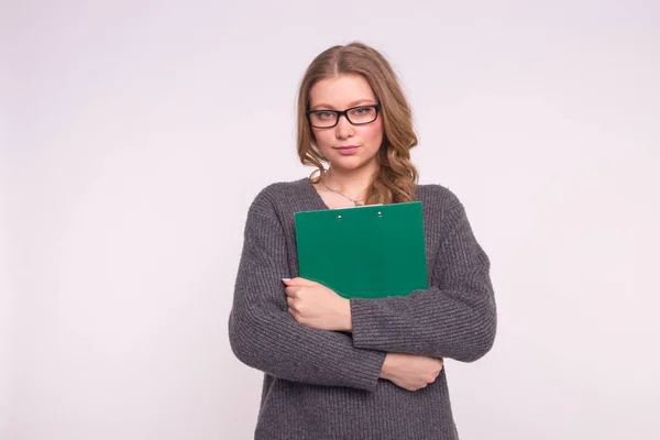 Junge Studentin mit schwarzer Brille posiert mit grünem Ordner auf weißem Hintergrund — Stockfoto