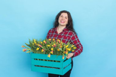 Lale mavi zemin üzerine bir kutu tutan mutlu genç kadın