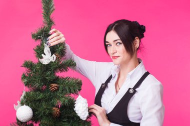 Noel, tatil ve insanlar kavramı - mutlu kadın pembe bir arka plan üzerinde Noel ağacı süsleme