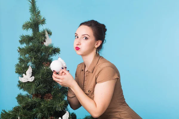 Boże Narodzenie, święta i ludzi pojęcie - młoda kobieta śmieszne dekorowanie choinki na niebieskim tle — Zdjęcie stockowe
