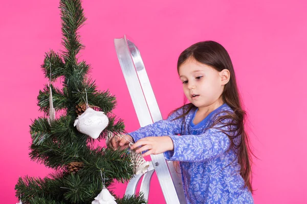 Kleines Mädchen mit Weihnachtsbaum auf rosa Hintergrund — Stockfoto