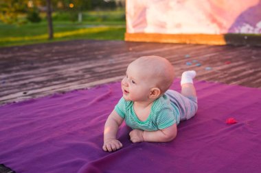 Cute child baby boy lying on blanket in summer day on nature. Family picnic in a park. clipart