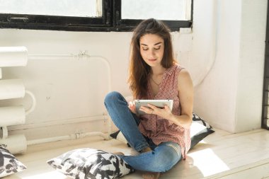 Teknoloji ve insan kavramı - tablet ve yastık ile ahşap eşiğinde oturan genç güzel kadın