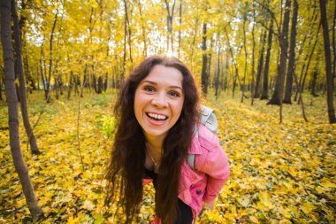 Heyecanlı neşeli genç kadın kamera sonbahar doğada neşeli bakarak.