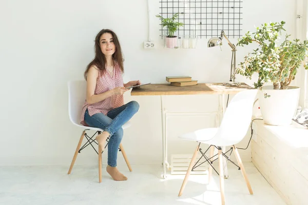 kişi, iç ve teknoloji kavramı - genç kadın bir masada dijital tablet ile odasında oturuyordu.