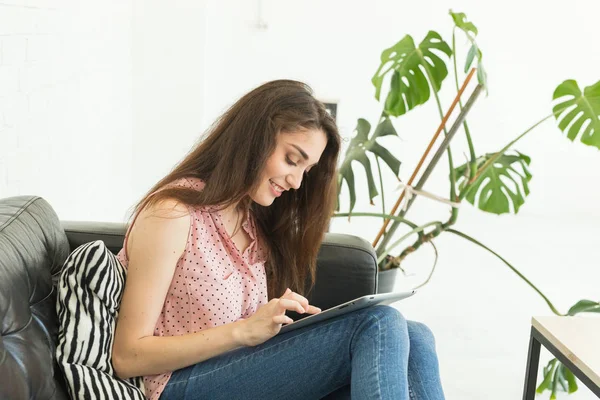 Concept de technologie et de personnes - jeune femme allongée sur le canapé sombre avec tablette — Photo