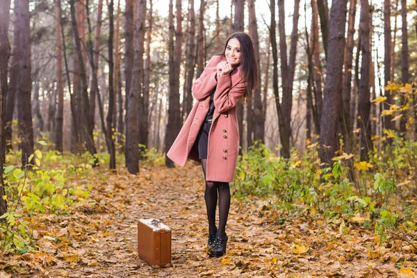 Season, nature and people concept - Woman in autumn park walking with retro suitcase — Stock Photo, Image