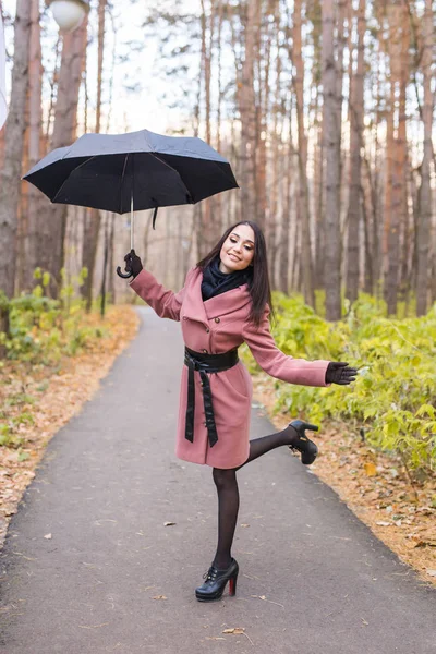 Val en mensen concept - jonge vrouw veel plezier onder paraplu in herfst park — Stockfoto