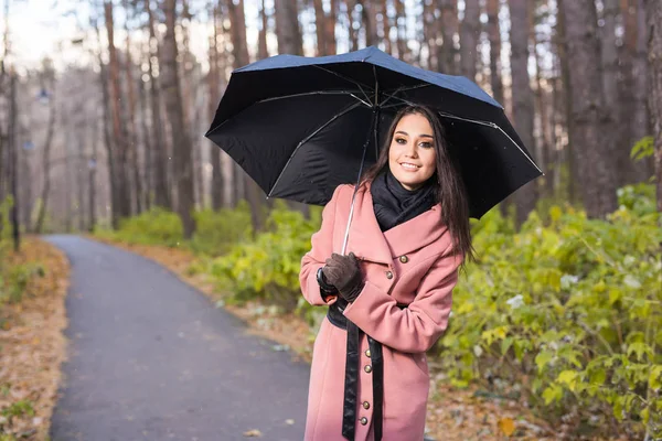 Gelukkige vrouw met paraplu onder de regen tijdens wandeling in de herfst natuur. — Stockfoto