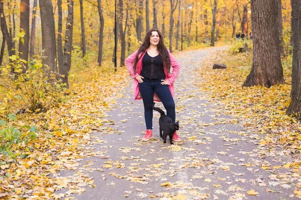 Mensen, huisdieren eigenaar en seizoen concept - plus grootte vrouw en een zwarte kat in de herfst park — Stockfoto