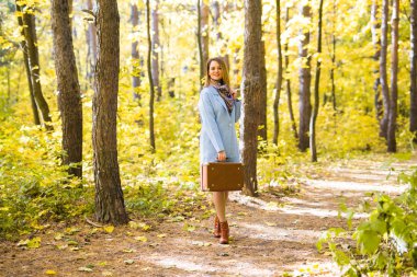 Sonbahar, moda, insanlar kavramı - kadın sonbahar parkta yürüyüş ve gülümseyen kahverengi retro çanta