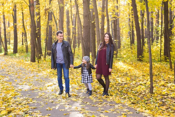 People, family and leisure concept - mixed race father and mother have fun in autumn park with their daughter — Stock Photo, Image