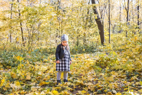 Παιδιά, το φθινόπωρο και οικογενειακό concept - μικρό κορίτσι παίζει με τα πεσμένα φύλλα στο πάρκο — Φωτογραφία Αρχείου