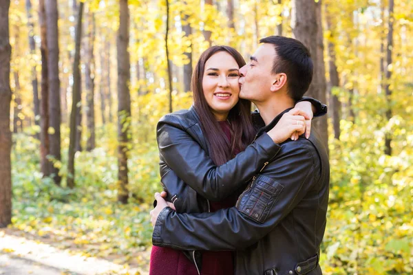 Kärlek, relation, familj och människor koncept - leende par kramas i höstparken — Stockfoto