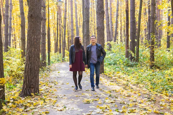 Pareja enamorada cogida de la mano y caminando por un parque en un día soleado de otoño — Foto de Stock