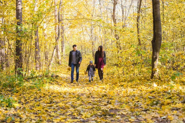 Pessoas, família e conceito de lazer - família feliz com a filha andando no parque de outono — Fotografia de Stock