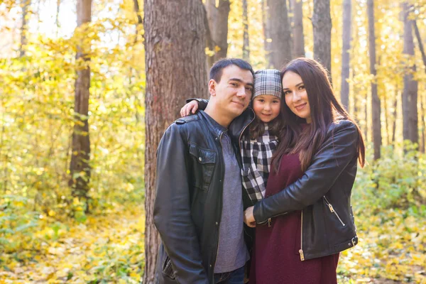 Conceito de paternidade, queda e pessoas - família jovem feliz no parque de outono — Fotografia de Stock