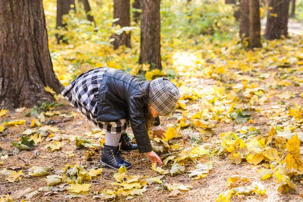 Otoño, naturaleza y concepto de la infancia - niño pequeño y feliz jugando en el parque con hojas amarillas —  Fotos de Stock