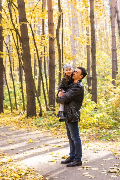 Familia, otoño, concepto de personas - padre e hija caminando en el parque de otoño. Hija en las manos de los padres — Foto de Stock