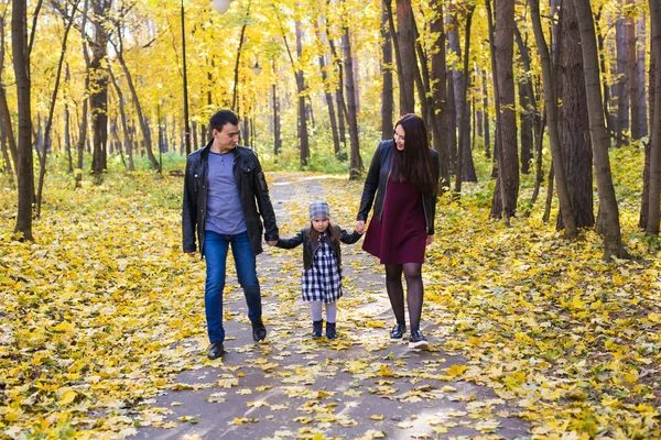 Concepto de personas, familia y ocio: madre, padre e hija se divierten en el parque de otoño — Foto de Stock