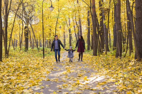 Люди, сім'я та концепція дозвілля - щаслива сім'я з дочкою, що йде в осінньому парку — стокове фото