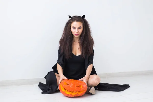 Joyeux gothique jeune femme en costume de sorcière halloween souriant sur fond de chambre blanche — Photo