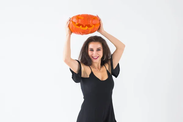 Aufgeregte, fröhliche junge Frau im Halloween-Kostüm posiert mit geschnitztem Kürbis vor hellem Hintergrund mit Kopierraum — Stockfoto