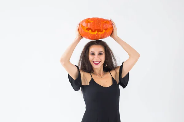 Mulher morena sorridente em maquiagem halloween posando com abóbora esculpida — Fotografia de Stock