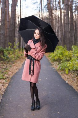 Sezon, sonbahar ve insanlar kavramı - pembe ceket siyah şemsiye ile gülümseyen güzel kadın portresi