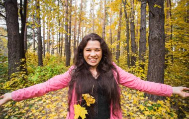 Sonbahar, sevinç ve insanlar kavramı - genç kadın sonbahar parkta eğleniyor. O bir gökyüzünde sarı yapraklar atıyor