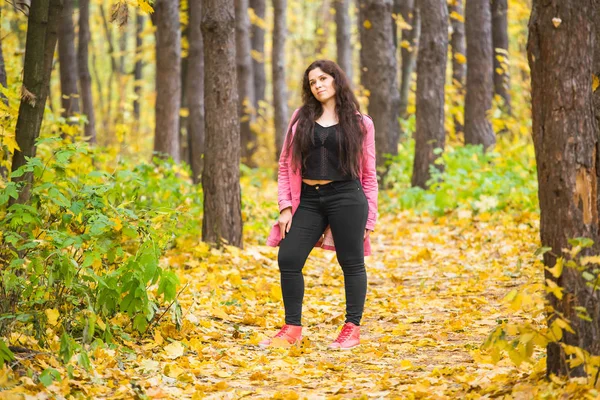 Young stylish plus size woman walking in autumn park — Stock Photo, Image