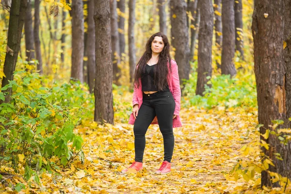 Weer, seizoen, mensen concept- plus grootte vrouw in roze jas over de herfst natuur-achtergrond — Stockfoto