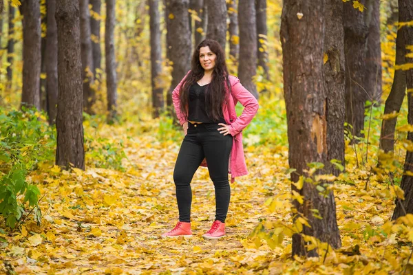 Météo, saison, concept de personnes - plus la taille femme en manteau rose sur le fond naturel d'automne — Photo